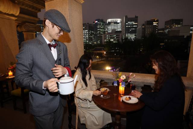 15일 서울 덕수궁 석조전에서 진행된 2024년 상반기 '밤의 석조전' 사전행사에서 방문객들이 서울 야경을 배경으로 2층 테라스 카페를 즐기고 있다. 연합뉴스