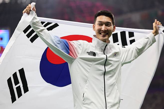 우상혁이 지난해 항저우 아시안게임 육상 남자 높이뛰기 결선에서 은메달을 딴 뒤 태극기를 둘러메고 있다. 연합뉴스