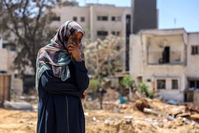 한 여성이 17일(현지시간) 팔레스타인 가자지구 가자시티 알시파 병원 인근에서 이스라엘군 공습으로 사망한 시신 수습 작업을 지켜보고 있다. AFP연합뉴스