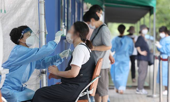 정부가 코로나19 감염병 등급을 2급에서 4급으로 하향 조정하겠다고 밝힌 뒤 2023년 8월23일 대구 달서구보건소 선별진료소에서 의료진이 코로나19 검사를 하고 있다. ⓒ연합뉴스