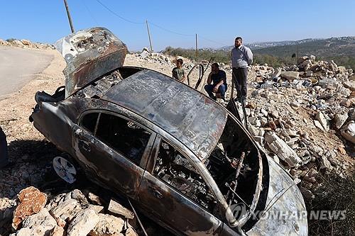 팔레스타인인들이 지난해 12월 요르단강 서안의 한 마을에서 불탄 차를 살펴보고 있다. [EPA 연합뉴스 자료사진. 재판매 및 DB 금지]