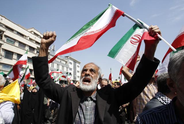 이란인들이 19일 수도 테헤란에서 이란 국기를 흔들며 '이스라엘 규탄' 구호를 외치고 있다. 테헤란=EPA 연합뉴스