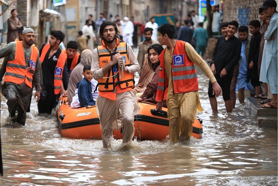 15일 폭우로 홍수 피해를 입은 파키스탄의 한 마을에서 구호단체들이 보트로 시민들을 태우고 이동하고 있다. EPA=연합뉴스