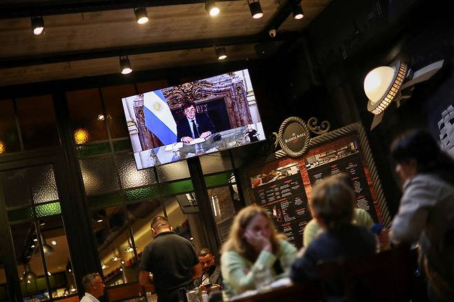 지난 22일(현지시간) 하비에르 밀레이 아르헨티나 대통령이 진행한 대국민 TV연설이 수도 부에노스아이레스의 한 식당에서 방영되고 있다. [사진=로이터연합]