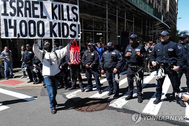 22일(현지시간) 미국 뉴욕 컬럼비아대 입구에 서 있는 경찰들 앞에서 친팔레스타인 구호를 외치는 시위대  [AFP 연합뉴스]