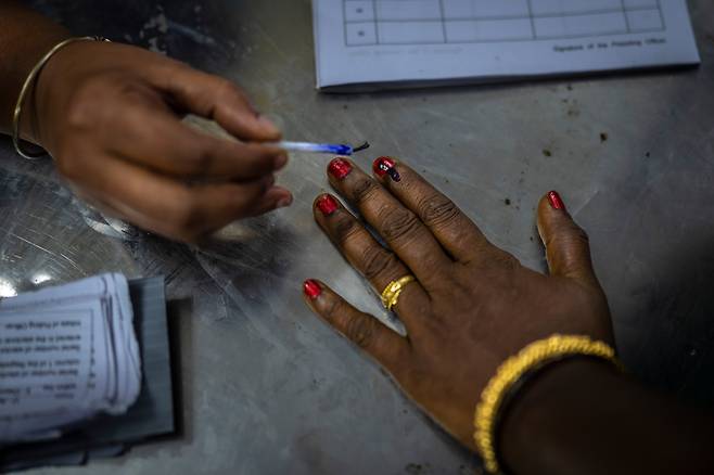 인도 총선 투표가 시작된 지난 19일 남부 타밀나두주 첸나이에서 한 투표관계자가 유권자의 검지손가락에 보라색 잉크를 바르고 있다. /AP 연합뉴스