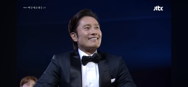 배우 이병헌이 7일 제60회 백상예술대상 시상식에서 이순재의 무대를 보고 미소를 짓고 있다. 유튜브 캡처