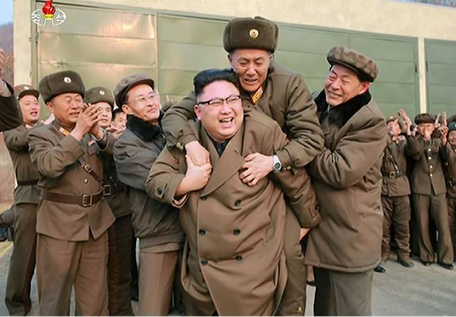 북한 김정은이 지난 2017년 3월 서해위성발사장에서 신형 고출력 로켓엔진 지상분출시험을 참관한 뒤 국방 과학·기술 책임자로 추정되는 관계자를 등에 업고 있다. /조선중앙TV 연합뉴스