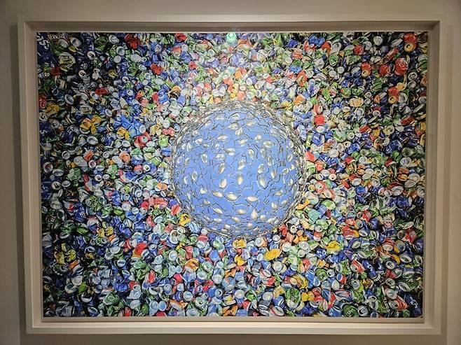 ‘블루’(설치) & ‘블루’(사진). 숟가락을 이어붙여 만든 반구 형태는 ‘이상적인 지구’이고, 주변 음료 캔들은 인간 탐욕이 부른 환경재난이다.