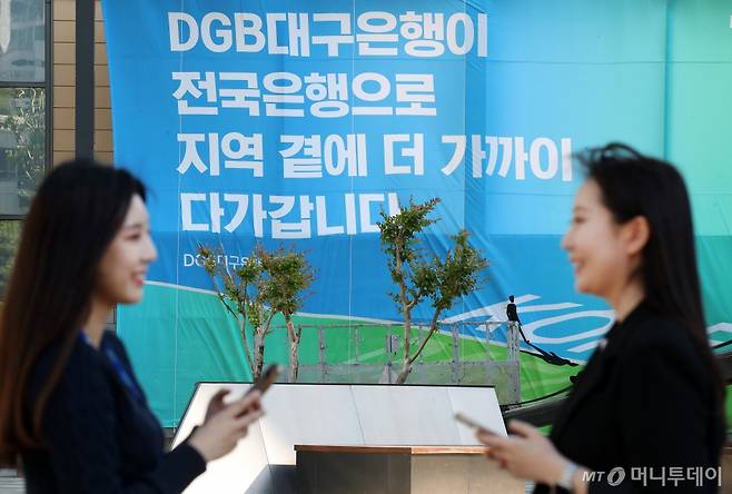 16일 오후 대구 수성구 대구은행 본점 앞 열린광장에서 은행 직원들이 '대구은행의 시중은행 전환 인가'를 축하하는 현수막 앞에서 환하게 웃으며 대화하고 있다. / 사진=뉴스1