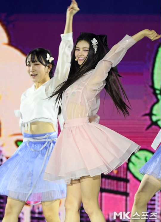 다니엘은 매우 길고 자연스러운 풀어헤친 헤어스타일로 무대에 등장했으며, 앞머리 없이 스타일링된 머리에는 섬세한 꽃 장식을 더해 청순하면서도 발랄한 분위기를 자아냈다.사진=MK스포츠 DB