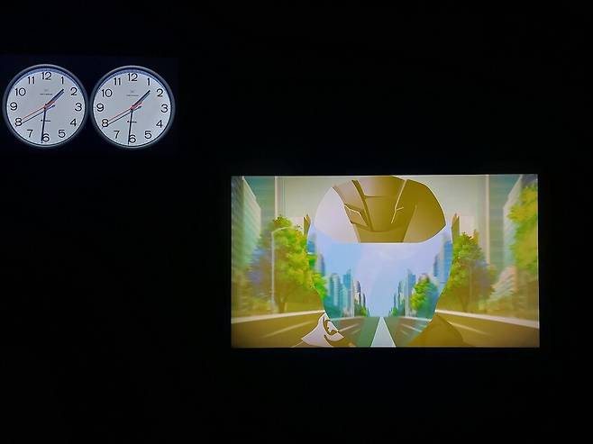 3층 들머리에 나온 호 추 니엔의 시간 이미지 영상물들. 오른쪽이 ‘모터사이클 공허’란 제목의 영상물이고 왼쪽 위에 있는 두개의 벽시계는 시간이 갈수록 어긋나는 숙명을 지닌 거장 펠릭스 곤잘레스 토레스의 설치물 ‘완벽한 연인’을 영상에 담은 작품이다. ‘…공허’에서는 사이클 라이더의 얼굴 부위가 작은 스크린이 되어 그 위로 도시가로를 질주하는 영상이 흘러간다. 호 추 니엔은 이 작품을 두고 말한다. “당신의 몸은 언제나 현재에서, 즉 과거와 미래의 경계선에서 움직인다. 당신의 정신은 더 자유롭다. 정신은 현재에 있지만, 사유한다. 무언가 기억하면, 그 순간 과거로 이동한다. 무언가 상상하면, 그 순간 떠올릴 수 있는 모든 가능한 미래들로 이동한다.” 노형석 기자