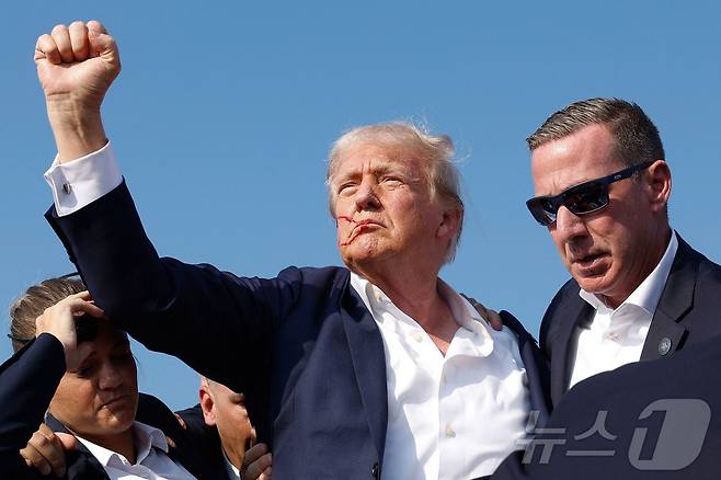 도널드 트럼프 전 미국 대통령이 13일 (현지시간) 펜실베이니아주 버틀러에서 열린 선거 집회서 유세를 하던 중 총격 사건이 발생해 얼굴에 핏자국을 묻은 채로 주먹을 불끈 쥐고 있다. 2024.07.14 ⓒ AFP=뉴스1 ⓒ News1 우동명 기자