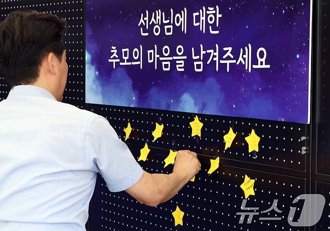 서이초 교사 순직 1주기(18일)를 앞둔 15일 서울 종로구 서울시교육청에 마련된 서이초 교사 1주기 추모 공간에서 교육청 직원이 추모의 마음을 담아 쓴 글을 붙이고 있다. 2024.7.15/뉴스1 ⓒ News1 박정호 기자