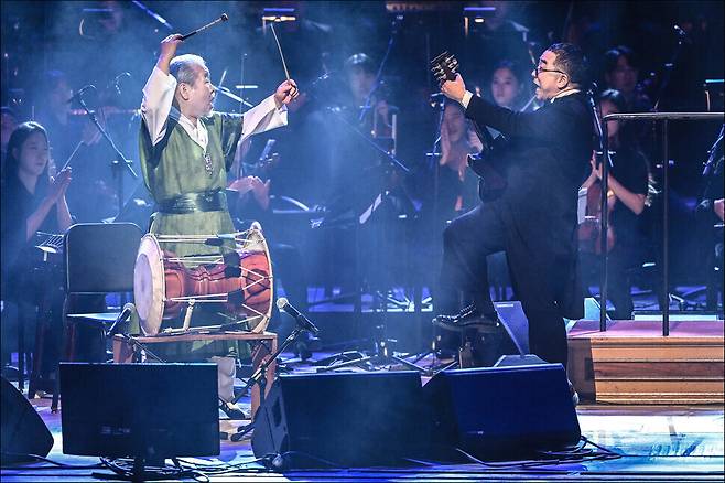 지난해 10월11일 서울 세종문화회관 대극장에서 열린 ‘김수철과 동서양 100인조 오케스트라’ 공연에서 김수철(오른쪽)과 김덕수가 ‘기타산조와 장구’를 연주하고 있다. 세종문화회관 제공