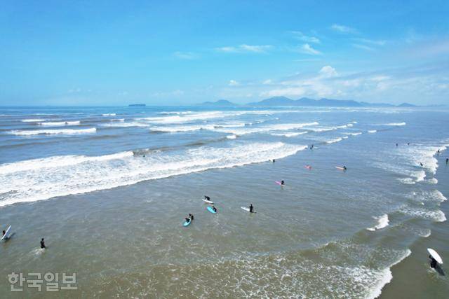 부산 다대포해수욕장에서 서퍼들이 파도를 즐기고 있다. 얇고 길게 퍼지는 파도라 초보자들이 즐겨 찾는다. 바다 건너 신공항이 들어설 예정인 가덕도와 거제도가 보인다.