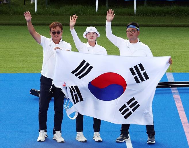 김우진과 임시현이 2일(현지시각) 프랑스 파리 앵발리드에서 열린 2024 파리 올림픽 양궁 혼성 단체 결승 독일과의 경기에서 승리한 뒤 박성수 감독과 함께 태극기를 흔들고 있다. 파리/올림픽사진공동취재단