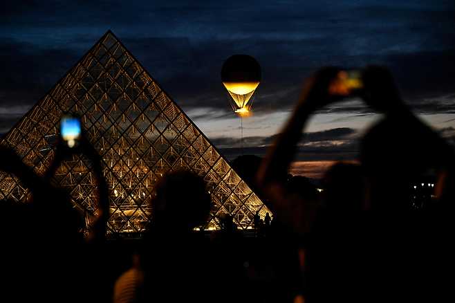 파리 시내에서 열기구 형태의 올림픽 성화대를 촬영하는 사람들.