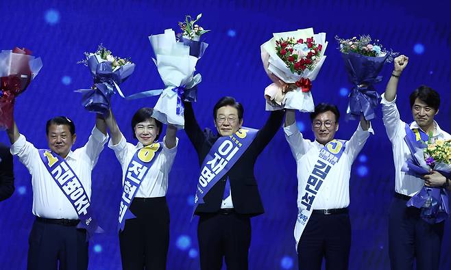 이재명 더불어민주당 대표와 최고위원들이 18일 오후 서울 송파구 KSPO DOME(올림픽체조경기장)에서 열린 제1차 정기전국당원대회에서 손을 맞잡아 들어보이며 당원들에게 인사하고 있다. /뉴스1