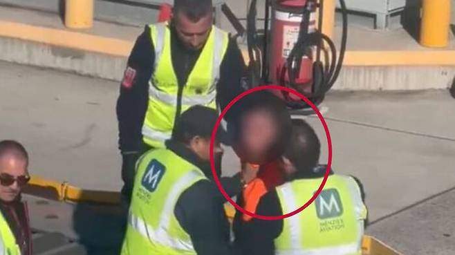 비행기 비상구 문을 강제 개방한 남성이 공항 직원들에 의해 제압되는 모습.(사진=엑스(옛 트위터) 캡처)