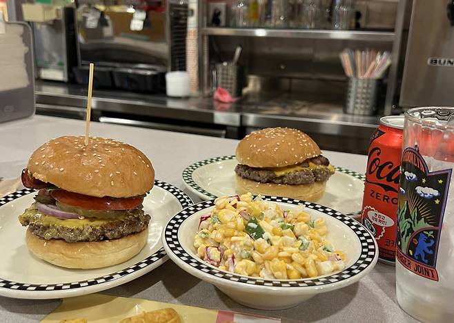"Brooklyn Works" (left) and "The Cheese Burger" are served with corn salad at Brooklyn the Burger Joints' Garosugil branch in Seocho-gu, Seoul, Sept. 6. (Kim Jae-heun/The Korea Herald)
