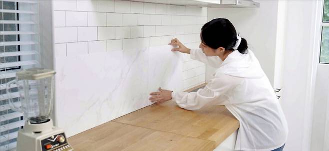 한솔홈데코 모델이 친환경 벽지 ‘한솔 이지셀프’를 벽면에 붙이고 있다. 한솔홈데코 제공