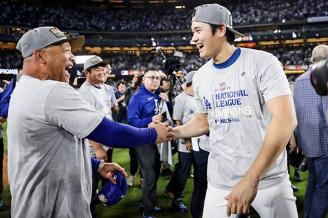 21일 미국 캘리포니아주 다저스타디움에서 열린 메이저리그 내셔널리그 챔피언 결정전 6차전에서 LA 다저스가 뉴욕 메츠를 꺾고 월드시리즈 진출을 확정한 뒤 LA 다저스의 오타니 쇼헤이(오른쪽)와 데이브 로버츠 감독이 서로 손을 잡고 기뻐하고 있다. /EPA 연합뉴스