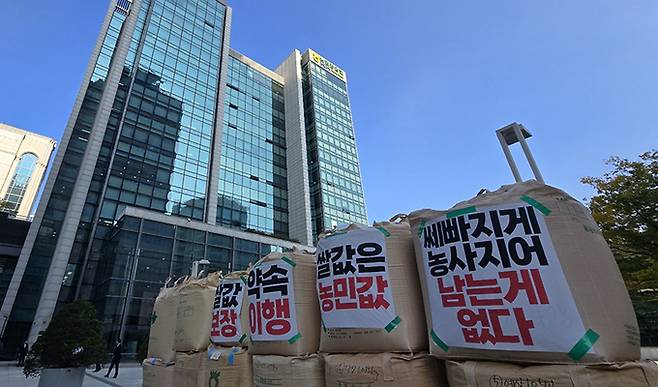 전국농민회총연맹(이하 ‘전농’)과 전국쌀생산자협회가 24일 오후 서울 농협중앙회 본관 앞에서 기자회견을 열고 나락값 7만원 공약 이행 등 즉각적인 쌀값 안정화 대책 마련을 촉구하는 가운데 쌓인 나락포대에 항의 문구가 붙어 있다.