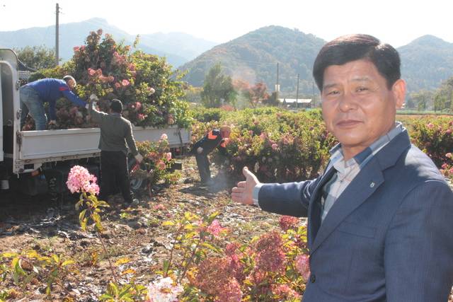 유해광 전북 완주 소양농협 조합장이 조경수 묘목 재배 농가를 찾아 트럭 적재 작업을 살펴보며 조경수 생산 과정을 설명하고 있다.