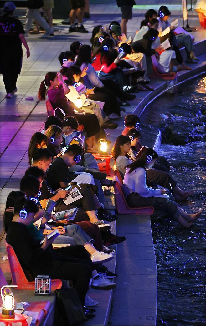 지난 9월6일 저녁 서울 청계천 일대에서 ‘책 읽는 맑은 냇가’ 행사의 일환으로 열린 ‘사일런트 야!한책멍’ 프로그램에서 참가자들이 헤드폰으로 음악을 들으며 책을 읽고 있다. 연합뉴스