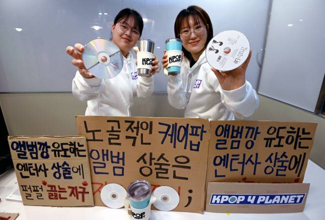 “텀블러 쓰고 지구 살려요”… 11일 서울 종로구 한 공유오피스에서 ‘케이팝포플래닛’ 활동가 박진희(25·오른쪽)·김나연(19) 씨가 ‘앨범깡 유도하는 엔터사 상술에 펄펄 끓는 지구’ 등 문구가 담긴 플래카드와 함께 자신들이 쓰는 텀블러를 들어 보이고 있다. 윤성호 기자