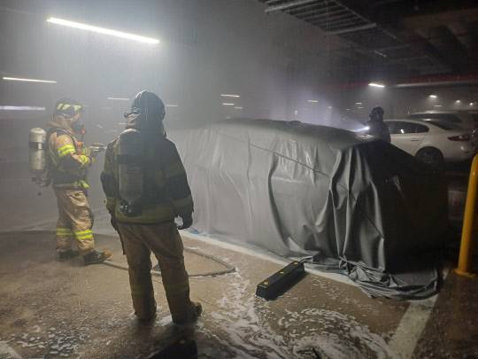 14일 새벽 2시14분쯤 아산시 모종동의 한 아파트 지하 주차장에서 화재가 발생한 전기차 벤츠EQC400 모델에 소방대원들이 질식소화포를 덮어 진압하고 있다. 아산소방서 제공