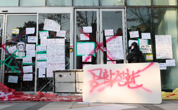 동덕여자대학교의 남녀공학 전환 추진 논의에 반발한 학생들이 지난 12일 오전 서울 성북구 동덕여대 본관에서 항의하며 건물 안쪽에서 문을 막고 서 있다.ⓒ연합뉴스