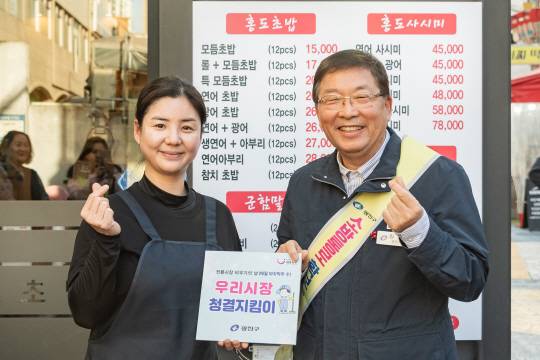 김경호(오른쪽) 광진구청장이 지난 19일 전통시장 비우기의 날을 맞아 우수 점포로 선정된 ‘홍도초밥’에 표지판을 전달하고 있다. 광진구청 제공