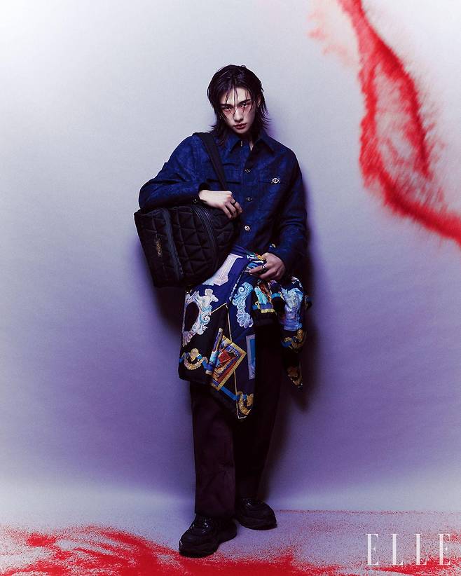 자카르 카펜터 재킷과 코튼 팬츠, 허리에 묶은 나일론 블루종, 퀼팅 디테일을 더한 나일론 백팩과 블랙 ‘머큐리’ 스니커즈는 모두 Versace.