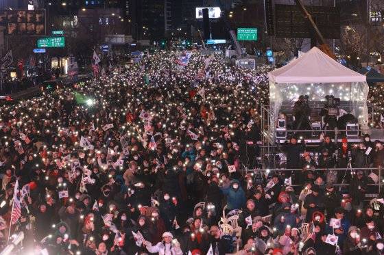 7일 서울 광화문 동화면세점 앞에서 '자유 대한민국 수호 광화문 국민혁명대회' 참가자들이 김건희 여사 특검법 부결과 대통령 탄핵소추안에 관한 소식을 듣고 기뻐하고 있다. 연합뉴스