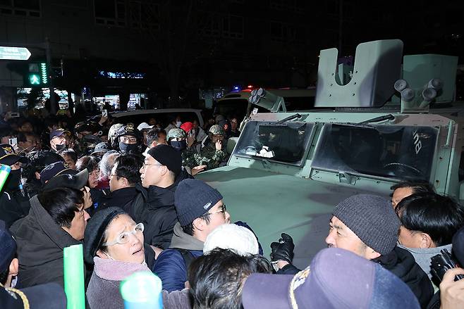 2024년 12월4일 새벽, 국회의사당 밖에서 시민들이 군용 차량을 둘러싸고 있다. ⓒEPA