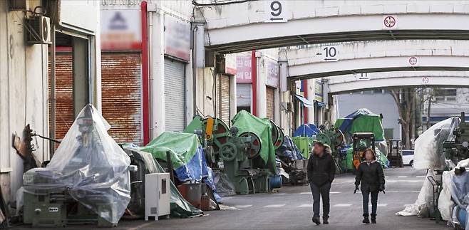 < 안 팔리는 중고기계만 덩그러니 > 경기 시흥 시화기계유통단지에 밀집한 상가마다 팔리지 않은 대형 중고 기계들이 방수 천막에 씌워진 채 방치돼 있다. 썰렁한 거리를 지나는 행인이 기계들을 쳐다보고 있다. /임형택 기자
