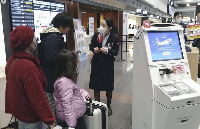 지난 26일 일본 도쿄의 하네다 국제공항에서 일본항공(JAL) 직원이 승객들의 항공기 탑승을 돕고 있다. 뉴시스