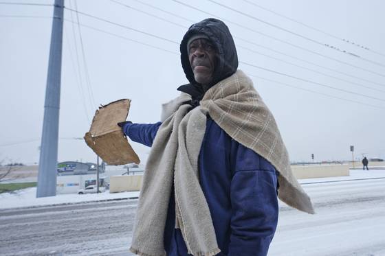 9일(현지시각) 눈이 내린 미 텍사스 주에서 한 노숙인이 담요를 이용해 추위를 피하고 있다. AP=연합뉴스