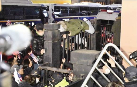 도 넘은 시위대 - ‘내란 우두머리’ 혐의를 받는 윤석열 대통령에 대한 구속영장이 발부된 19일 새벽 윤 대통령 지지자들이 영장을 발부한 서울 마포구 서울서부지방법원에 몰려들며 담장을 넘고 있다. 이들은 경찰로부터 빼앗은 방패나 플라스틱 의자 등으로 법원 정문과 유리창을 깨부수며 법원에 침입했다. 헌법기관인 법원에 시위대가 난입한 것은 헌정사상 초유의 일이다. 도준석 전문기자