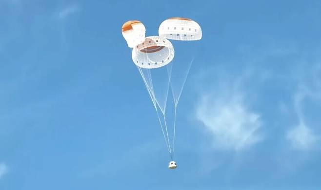 블루오리진의 뉴셰퍼드 캡슐이 4일(현지시각) 달 중력 시뮬레이션을 위한 준궤도 비행을 마치고 지상으로 돌아오고 있다. 3개 낙하산 중 하나는 처음엔 완전히 펼쳐지지 않았다가 착륙 직전 완전히 펼쳐졌다. 웹방송 갈무리