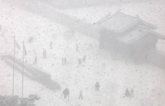 서울에 대설주의보가 내려진 6일 오후 서울 종로구 경복궁에서 시민들이 눈을 맞으며 길을 걷고 있다. 뉴스1