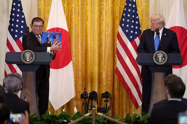 일본의 이시바 시게루 총리가 7일 워싱턴 백악관에서 열린 미일 정상회담 기자회견 중 도널드 트럼프 대통령이 선물한 트럼프 홍보 책자를 들어 보이고 있다. /AP 연합뉴스