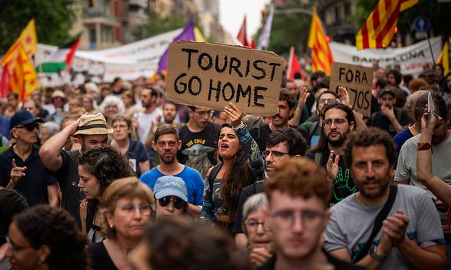 스페인 바르셀로나 주민들이 지난 2024년 6월19일(현지시간) 시내 중심가에서 ‘관광객들은 집으로 돌아가라’는 문구가 적힌 손팻말을 들고 과잉관광에 항의하는 구호를 외치고 있다. 바르셀로나=AP연합뉴스