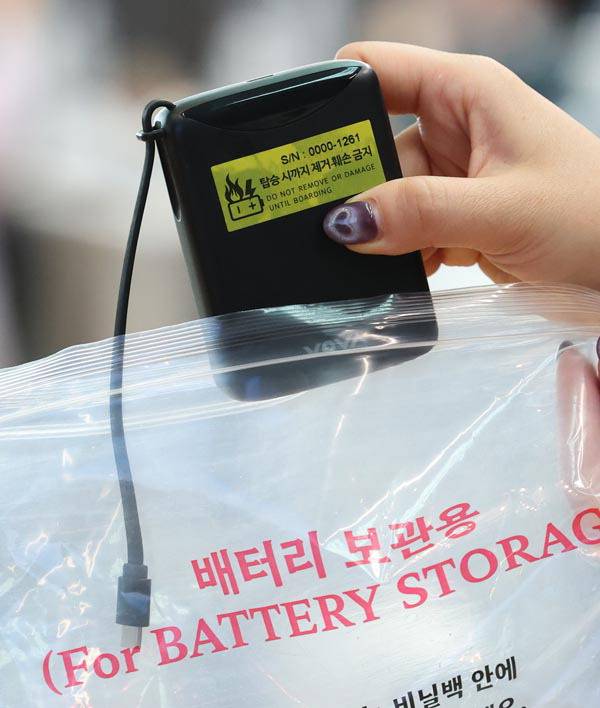 지난 1일 인천국제공항 대한항공 체크인 카운터에서 관계자가 보조배터리에 스티커를 부착한 뒤 비닐봉지에 넣는 모습. 연합뉴스