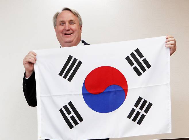 2012년 3월 21일 오후 경기도 과천 법무부청사에서 인요한(53·미국명 존 린턴) 박사가 권재진 법무장관으로부터 대한민국 국적 증서를 받고, 태극기를 들어 보이며 웃고 있다./이태경 기자