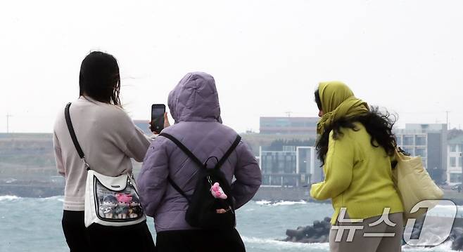 평년보다 높았던 기온이 뚝 떨어진 16일 오전 제주시 도두동 무지개 해안도로에서 패딩을 입은 관광객들이 사진을 찍고 있다. 2025.3.16/뉴스1 ⓒ News1 오현지 기자