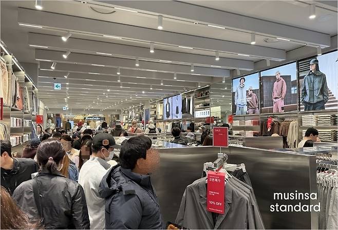 사람들이 무신사 스탠다드 롯데월드몰 잠실점 매장에서 쇼핑하고 있다.