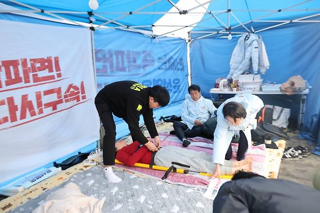 윤석열 대통령 탄핵심판 선고를 촉구하며 단식하던 정혜경 진보당 의원(사진 속 붉은 상의)이 27일 오전 병원으로 이송되고 있다. 진보당 제공